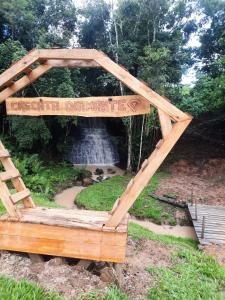 a wooden arch with a fountain in the background at CascataDiamantePousada in Laurentino