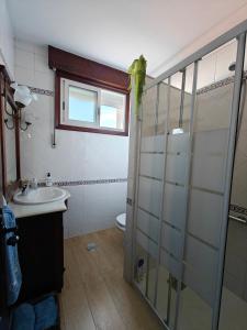 La salle de bains est pourvue d'une douche en verre et d'un lavabo. dans l'établissement A Casa do Choco, à Redondela