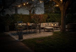 d'une terrasse avec une table, des chaises et des lumières. dans l'établissement Venez Chez Vous - Villa Magnolia, à Annecy