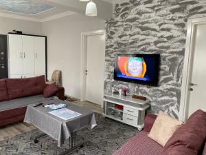 een woonkamer met een bank en een tv aan de muur bij Gökçen Home in Pamukkale