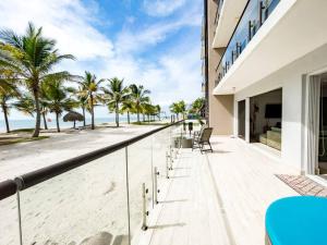 a balcony with a view of the beach and palm trees at Olas del Mar by Playa Caracol Residences in Punta Chame