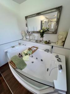 a white bath tub in a bathroom with a mirror at Engel Ingold Lodge Chalet "Bärgblümli" in Habkern