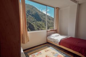a bedroom with a large window with a mountain view at Backpackers-balcones-river-lodge in Baños