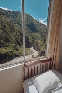 a bedroom with a window with a view of a mountain at Backpackers-balcones-river-lodge in Baños