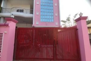 ein rosafarbenes Gebäude mit einem roten Zaun davor in der Unterkunft Goroomgo Hotel Kashi Nest Varanasi - A Peacefull Stay & Parking Facilities in Varanasi