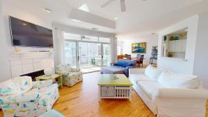 a living room with a white couch and a tv at 6-B 13th Street by Tybee Vacation Rentals in Tybee Island