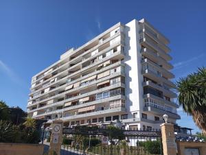 un alto condominio bianco con una palma di playa colina a Torremolinos