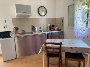 a kitchen with a table and a clock on the wall at chez Béatrice in Porto-Vecchio