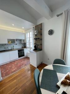 a kitchen with white cabinets and a table with chairs at VUE SUR LA SEINE in Paris