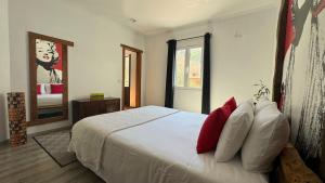 Schlafzimmer mit einem Bett mit weißer Bettwäsche und roten Kissen in der Unterkunft The Modern & Recycled House in Machico