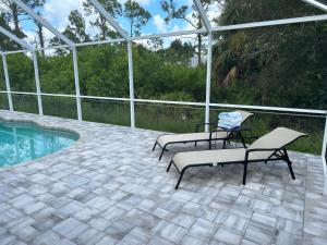 eine Terrasse mit zwei Stühlen und einem Swimmingpool in der Unterkunft Paradise in the forest in Lehigh Acres