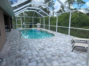 eine Terrasse mit einem Pool mit einer Pergola in der Unterkunft Paradise in the forest in Lehigh Acres