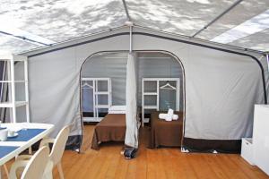 uma tenda com uma cama, uma mesa e cadeiras em Riva di Ugento Beach Camping Resort em Ugento