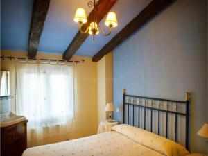 a bedroom with a bed with a chandelier and a window at Casa Rural Zaragoza in Almonacid de la Sierra