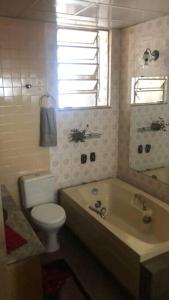 ein Bad mit einer Badewanne, einem WC und einem Fenster in der Unterkunft Vista para o Parque Moscoso in Vitória
