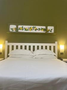una camera da letto con un grande letto bianco con due luci di San Domenico Residence by BADIA NUOVA a Trapani
