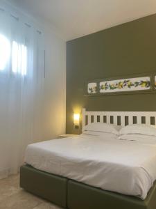 a bedroom with a white bed with a green wall at San Domenico Residence by BADIA NUOVA in Trapani