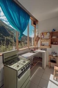 eine Küche mit einem Herd und einem großen Fenster in der Unterkunft Backpackers-balcones-river-lodge in Baños