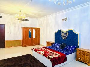 a bedroom with a blue bed and a chandelier at Tranquil Haven King Bed Ensuite Fully Furnished Bedroom in Ajman 