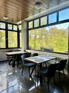 a restaurant with tables and chairs and large windows at Waldhotel Bad Münstereifel in Bad Münstereifel