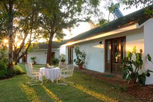 een tafel en stoelen in de tuin van een huis bij The Musketeers Lodge in Bulawayo