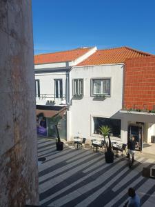 a courtyard in a building with tables and chairs at Plaza Caparica Hostel in Costa da Caparica