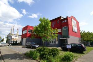 a red building with cars parked in a parking lot at 220 qm Penthouse Wohnung mit Fahrstuhl in Mannheim