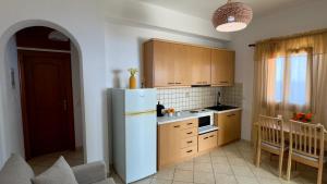La cuisine est équipée d'un réfrigérateur blanc et de placards en bois. dans l'établissement Aegean Balcony, à Áno Meriá