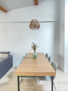 a dining room with a wooden table with a vase on it at Le Refuge du Port, parking privé gratuit in La Ciotat