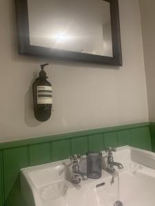 een wastafel in de badkamer met een zeepdispenser op een spiegel bij The Fox & Hounds Inn in Dorchester