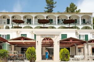 uma mulher em pé em frente a um hotel em Hotel Apollon Corfu em Paleokastritsa