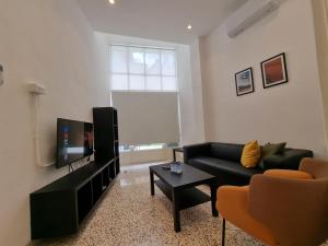 sala de estar con sofá negro y TV en Downtown Living Boutique Apartments, en Amán