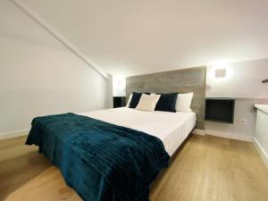 sypialnia z dużym łóżkiem i niebieskim kocem w obiekcie Las Barajas de Saturno w Madrycie