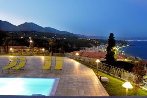 a pool with yellow chairs and a view of the water at Residence Villa Beuca in Cogoleto