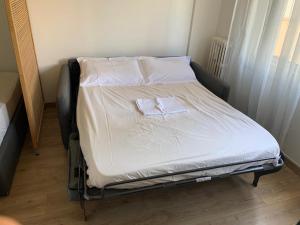 - un petit lit avec des draps blancs et des oreillers dans l'établissement Bel appartement avec emplacement idéal, à Saint-Laurent-du-Var