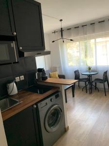 une cuisine avec un lave-linge et une table avec des chaises dans l'établissement Bel appartement avec emplacement idéal, à Saint-Laurent-du-Var
