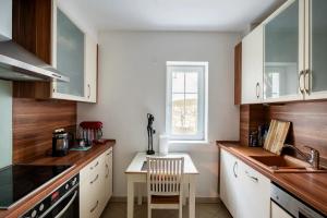 uma cozinha com armários brancos e uma mesa com uma cadeira em Comfortable room in central location em Hamburgo