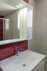 DANA HOTEL APARTMENTs في سارنده: حمام مع حوض أبيض ومرآة