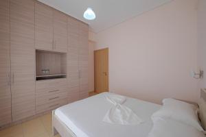 DANA HOTEL APARTMENTs في سارنده: غرفة نوم بسرير ابيض وتلفزيون