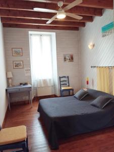1 dormitorio con 1 cama y ventilador de techo en Maison d'Hôtes La Prévôté, en Périssac