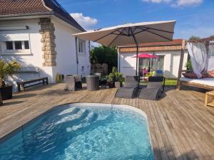 een zwembad op een houten terras met een parasol bij La Balinaise Chambre indépendante avec jardin et piscine proche Chantilly, PARC ASTERIX et gare TER pour PARIS en 19min, à 15 min de Roissy CDG in Orry-la-Ville