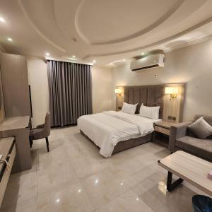 a hotel room with a bed and a couch and a table at بلند للشقق المخدومة اقتصادي in Dammam