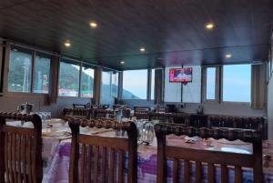 Hotel Snow Crest Inn - Natural landscape Mountain View في دارامشالا: غرفة طعام بها طاولات وكراسي وتلفزيون