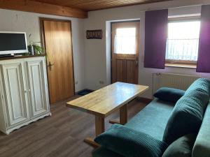 ein Wohnzimmer mit einem Sofa und einem Tisch in der Unterkunft Ferienwohnung auf dem Erlebnisreiterhof Kreipl in Grattersdorf