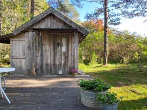 a wooden out house with a table and plants in front at Karlsäter - Lilla stugan in Älvkarleby