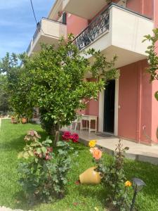 a house with a tree and flowers in the yard at lividio apartment in Lefkada