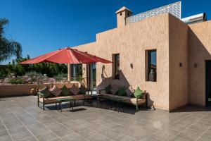eine Terrasse mit Sofas, einem Sonnenschirm und einem Tisch in der Unterkunft Villa Roseraie Isabella in Marrakesch