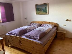 1 dormitorio con 1 cama de madera con 2 almohadas en Ferienwohnung auf dem Erlebnisreiterhof Kreipl en Grattersdorf