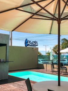 a large umbrella over a swimming pool with a table and chairs at Pousada Aloha in Maceió