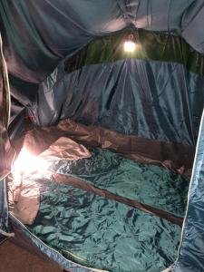 a small bed in a tent with a light on it at Tenda Photok Camping Reception in Funchal